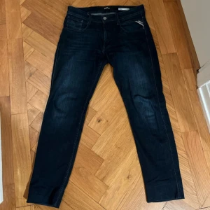 Mörkblå jeans från Replay - Snygga mörkblå jeans från Replay med dragkedja och knappstängning. Klassisk femficksdesign och en stilren look som passar perfekt till vardags. Märkesdetaljer på bakfickan ger en extra touch.