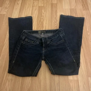 Mörkblå jeans med broderade bakfickor - Snygga mörkblå jeans med unika broderade detaljer på bakfickorna. De har en klassisk femficksdesign och en bekväm passform. Perfekta för en stilren look.