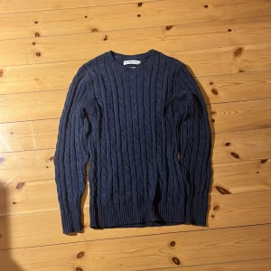 Mörkblå stickad tröja från S.C.W. - Säljer en snygg mörkblå stickad tröja från S.C.W. med kabelstickat mönster. Tröjan har långa ärmar och en rund halsringning. Perfekt för kyliga dagar! Den är oanvänd. Jag säljer för att den var för liten för mig. Hör av dig vid frågor🙏