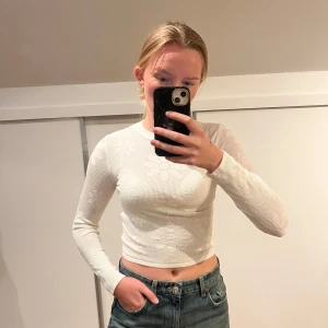 Vit ribbad croppad tröja - Säljer en stilren vit ribbad tröja med lång ärm och croppad passform. Perfekt för en trendig look. Liten i storleken. 