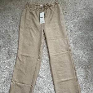 Beige linnebyxor från ONLY M - Snygga beige linnebyxor från ONLY med elastisk midja och avslappnad passform. Perfekta för en stilren och bekväm look.