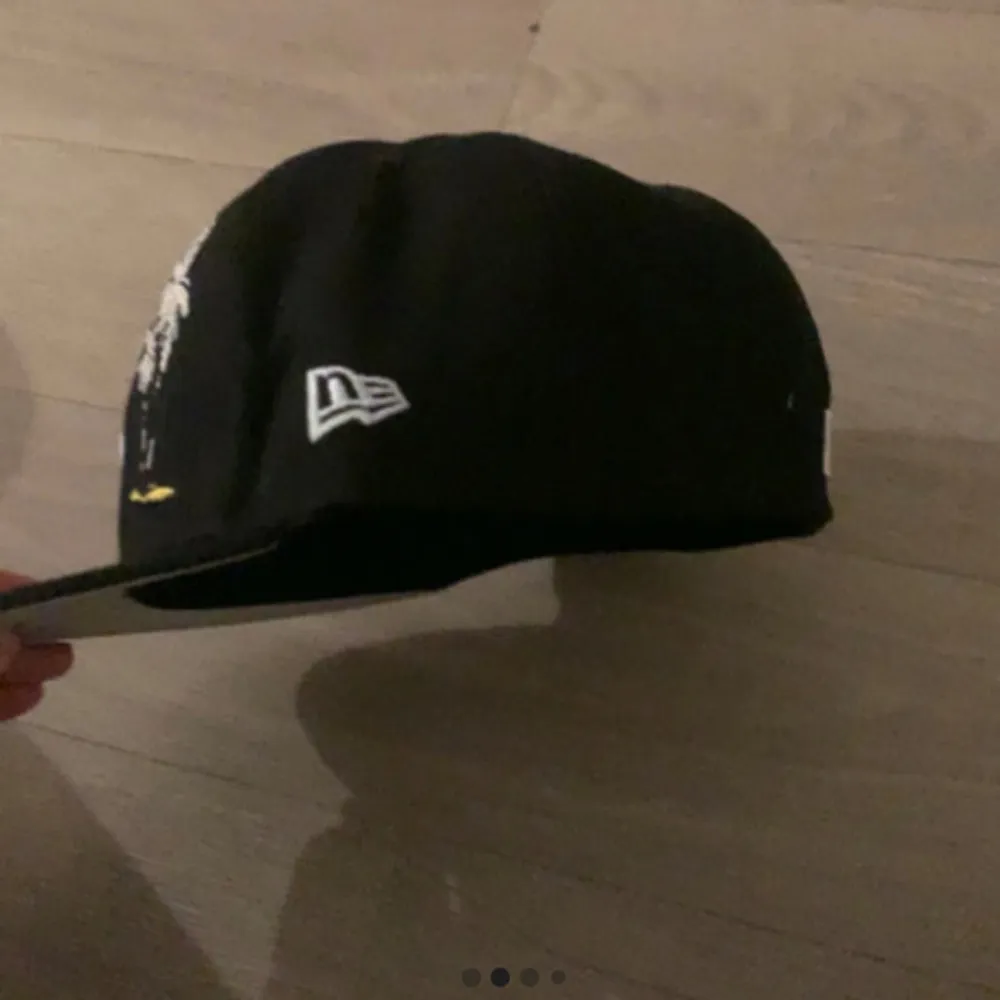 Snygg svart keps från New Era med LA-broderi framtill och palm-motiv på sidan. Kepsen har även ett märke för Dodger Stadiums 50-årsjubileum och ett litet hjärta baktill. Perfekt för att ge din stil en sportig touch.. Asusteet.