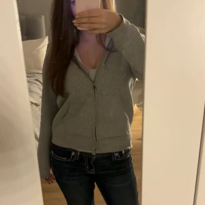 Grå huvtröja från Ralph Lauren - Säljer en grå huvtröja från Ralph Lauren med dragkedja och huva. Tröjan har långa ärmar och en liten logga på bröstet. Köptes i november 2024 men säljer pga jag inte använde den så mycke som jag trodde jag skulle💕