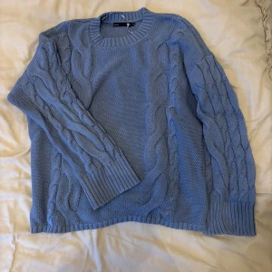 Blå stickad tröja från 157 - Säljer en snygg blå stickad tröja från 157 med kabelstickat mönster. Tröjan har långa ärmar och ribbstickade muddar vid ärmslut och nederkant. Perfekt för kyliga dagar!