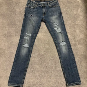 Blå jeans från Jack & Jones - Snygga blå jeans från Jack & Jones med slitna detaljer och en klassisk femficksdesign. Perfekta för en avslappnad stil med en touch av edge. DM om ni har några frågor! 