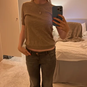 Beige kortärmad tröja - Säljer en stilren beige tröja med korta ärmar. Perfekt för en avslappnad look. Tröjan har en rund halsringning och är tillverkad i kashmir