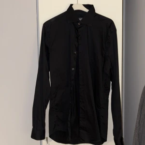 Svart skjorta från Dressmann - Svart skjorta från Dressmann i slim fit. Tillverkad i premium bomull med stretch för extra komfort. Endast använd vid något tillfälle.