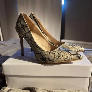 Ormmönstrade pumps med spetsig tå - Snygga ormmönstrade pumps med spetsig tå och hög klack. Perfekta för att ge en trendig touch till din outfit. Aldrig använda 