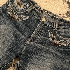 Blå jeans med broderade detaljer - Snygga blå jeans med unika broderade mönster på fickorna. Jag har sprättat upp dem längst ner för att de ska bli längre, är 168 för referens 