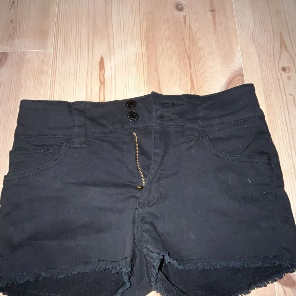 Snygga svarta shorts från H&M med mid waist midja och fransiga kanter. De har en dragkedja och knappar framtill för en cool look. Perfekta för varma sommardagar!. Shortsit.
