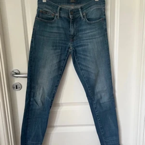 Blå jeans från Polo Ralph Lauren - Snygga blå jeans från Polo Ralph Lauren i modellen Tompkins Skinny Crop. De har en tight passform och är perfekta för en stilren look. Klassisk femficksdesign med knapp och dragkedja framtill.