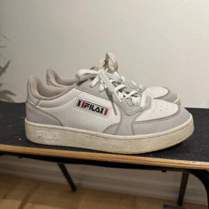 Vita sneakers från Fila - Snygga vita sneakers från Fila med grå detaljer och klassisk logga på sidan.  Använda men ändå väldigt fina. Hör gärna av dig vid intresse och om du har frågor. Priset kan alltid diskuteras 