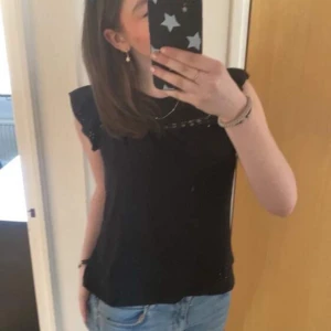 Svart blus med spetsdetaljer - Snygg svart ärmlös topp med spetsdetaljer vid axlarna🤩. Perfekt för en stilren look. Passar bra till jeans! Knappt använd, skriv vid eventuella frågor!💕 säljer en likadan i vit!