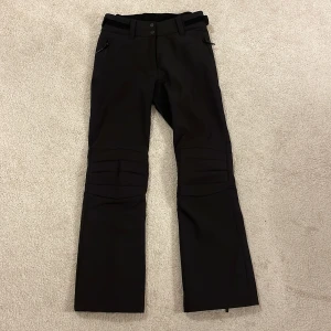 Svarta skidbyxor från McKinley - Snygga svarta byxor från McKinley med dragkedjor vid bensluten och knädetaljer. Någorlunda stretchiga då det är perfekt vid skidåkning! Skriv för fler bilder! 