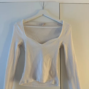 Vit ribbad topp - Säljer en stilren vit ribbad topp med långärmad design och v-ringad hals från Nelly🫶🏼💗 Storlek: S
