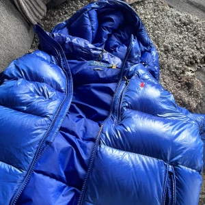 Ralph lauren jacka - Snygg blå dunväst från Polo Ralph Lauren med dragkedja och huva. Perfekt för kyliga dagar. Den har en liten röd logga på bröstet som ger en stilren touch. Aldrig använd och beställnings bekräftelse finns från boozt om det önskas 