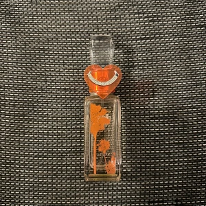 Juicy Couture Malibu Parfym (Edt) 40 ml - Säljer en Juicy Couture Malibu parfym med en unik flaska. Den har en fyrkantig form med ett hjärtformat lock i orange och silverdetaljer. Flaskan är dekorerad med orange blommönster och rymmer 40 ml. Perfekt för den som älskar en fräsch och livlig doft.