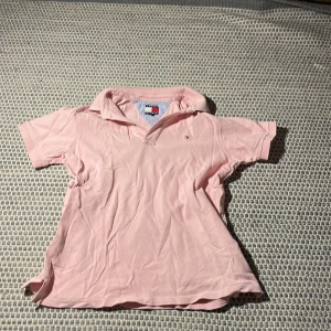 Rosa pikétröja från Tommy Hilfiger - Säljer en stilren rosa pikétröja från Tommy Hilfiger. Tröjan har korta ärmar och en klassisk krage. Perfekt för en avslappnad och snygg look. 💖