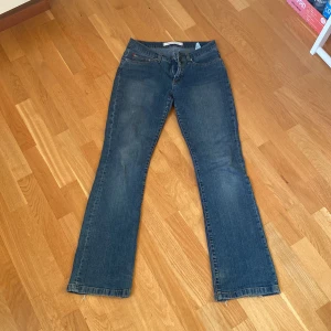 Blå jeans från Vero Moda - Säljer ett par klassiska blå jeans från Vero Moda. De har en bootcut-stil och är tillverkade i jeansmaterial. Jag köpte de på en loppis för ett år sen och det står inte vilken storlek men skulle säga att de sitter som 36. Andvänt skick och jag har sytt de på innerlåret, inget man ser men det finns där iaf bild på det på sista sliden.