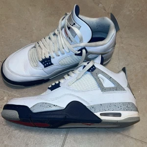 Nike Air Jordans i vitt och blått - Snygga Nike Air Jordans i vitt med blå detaljer. Skorna har en klassisk design med snörning och en bekväm passform. Perfekta för dig som älskar stil och komfort.