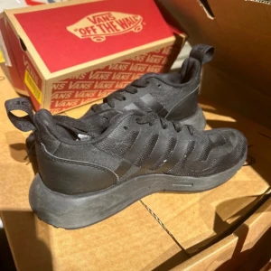 Svarta sneakers från Adidas - Snygga svarta sneakers från Adidas med en stilren design. Skorna har en bekväm sula och klassiska ränder på sidan. Perfekta för vardagsbruk och ger en sportig look.