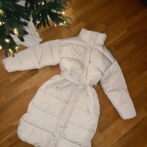 Cremevit slutsåld pufferjacka från Bik Bok - Så himla mysig och snygg lång jacka från Bikbok Har en likadan i svart men ångrade mig med den vita/creme då jag har barn och allt vitt blir smutsigt tyvär   Men är besatt av den svarta! Dem är sjukt snygga & så varma + älskar midjebandet som man kan knyta 🤍  Helt ny med prislapp så ett riktigt kap!!!! Nypris 999kr