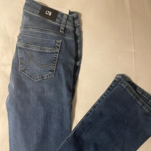 Blå jeans från LTB - Snygga blå jeans från LTB med klassisk femficksdesign och knappgylf. Perfekta för en avslappnad stil. Märkesdetaljer på knappen och baksidan av midjan ger en extra touch. HELT NYA!!
