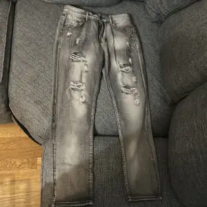Snygga grå jeans med slitningar på framsidan för en trendig look. De har en klassisk femficksdesign och en bekväm passform. Perfekta för en avslappnad stil.