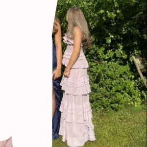 Balklänning - Elegant ljusrosa långklänning med flera volanglager. Perfekt för sommarens festligheter med en romantisk touch. Endast använd en gång, nypris ca 2000kr