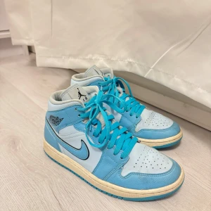 Nike Air Jordans i ljusblått och vitt - Snygga Nike Air Jordans i en fräsch ljusblå och vit färgkombination. Skorna har klassisk snörning och den ikoniska Air Jordan-loggan på sidan. Perfekta för en sportig och stilren look.    Sparsamt använda 
