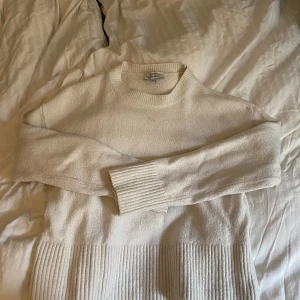 Vit stickad tröja från & Other Stories - Säljer en stilren vit stickad tröja från & Other Stories. Tröjan har en klassisk design med ribbade detaljer vid ärmslut och nederkant. 