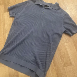 Blå pikétröja från Massimo Dutti - Snygg blå pikétröja från Massimo Dutti i extrafin bomull. Tröjan har en klassisk krage och korta ärmar, perfekt för en stilren look.                               -Otroligt skön                                                                 -Köpt från Massimo Dutti i Stockholm                     -M men passar även S