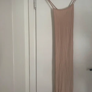 Beige klänning från Shein - Säljer en beige, axelbandslös klänning från Shein i storlek XS. Klänningen har justerbara axelband och är tillverkad i ett mjukt material. Perfekt för varma dagar. Har som man kan se ett litet hål men man ser knappt!