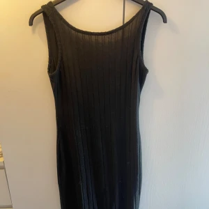 Klänning - Klänning med öppen rygg och slutar vid mitten på vaderna. I mycket gott skick 