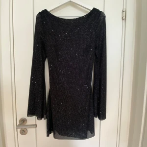 Svart glittrig klänning - Jättefin svart glittrig klänning med öppen rygg köpt på parthea. Endast använd 1 gång så i nyskick!