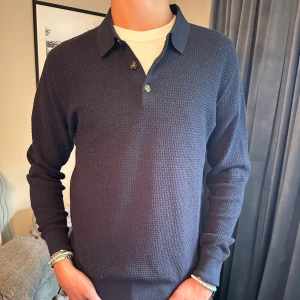 Mörkblå pikétröja - assnygg kragtröja med knappar från john henric. Tröjan har även lite textur. Storlek S men sitter som M. Nypris 999 kr