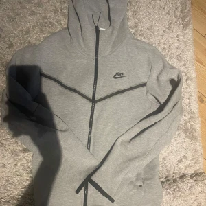 Nike tech - Säljer nu min gråa Nike tech zip hoodie. För att den inte passar längre. Tröjan är i såsom nyskick, inga hål, inte solbränd eller inga fel på den alls. Pris kan diskuteras vid snabb affär!