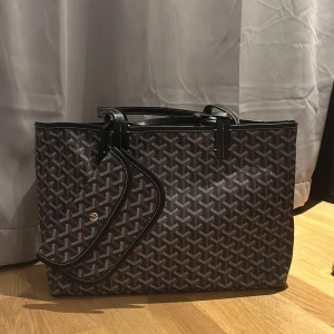 Goyardliknande väska - Ej äkta. Super snygg väska som liknar goyard väskan. Den har dragkedja och fack som visar i bilderna. Tryck på köp nu för att köpa💗 50 bred, 28 hög och 15 djup.