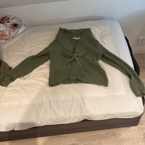 Grön stickad kofta från First Class - Säljer en superfin grön stickad kofta från First Class. Den är i storlek S (36-38) och har en söt knytning framtill. Perfekt för höst och vinter när man vill vara både varm och snygg. Koftan har långa ärmar och är riktigt mysig att ha på sig. Passar både till vardags och lite finare tillfällen. 💚