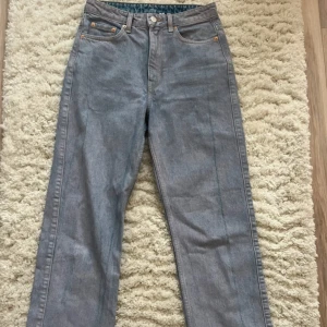 Lila- blå jeans från Weekday - Snygga grå jeans från Weekday med en klassisk straight fit. De har en hög midja och är tillverkade i denim med en stilren design. Perfekta för en avslappnad look.