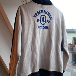 Nike vintage sweatshirt  - Nike vintage sweatshirt med dragkedja och tryck på ryggen.                                                           Mycket bra skick, en liten fläck under ena armen som knappt syns.                                             Storlek: XL från etiketten, men passar XS/S.      Mått: axelbredd - 50 cm, bredd från armhåla till armhåla - 53 cm, längd - 68 cm, armlängd - 53 cm