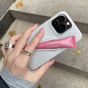 Mobilskal med läppglanshållare från Amore UF - Mobilskal med en hållare för läpprodukter i färgen Stone. Skalet passar IPhone 13/14/15 och rymmer flera olika läpprodukter och ger dessutom ett bra skydd för mobilen🥰🥰