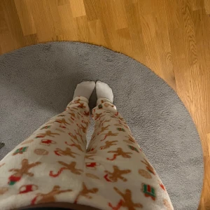 Vita mjukisbyxor med julmönster - Mysiga vita mjukisbyxor med julmönster av pepparkakor och polkagrisar. Perfekta för att hålla sig varm under vintern. Byxorna har en mjuk och fluffig yta.