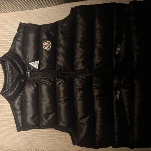 Moncler Gui väst - Säljer en snygg svart dunväst från Moncler. Säljs pga att den var för liten på min pojkvän. Skick 9/10. Det är storlek 2 som motsvarar S. Perfekt nu när vi går mot varmare tider! 