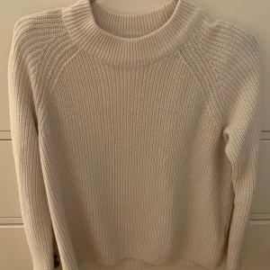 Beige stickad tröja - Säljer en stilren beige stickad tröja med rund hals och långa ärmar. Perfekt för kyligare dagar och enkel att matcha med olika outfits. Tröjan har en ribbad struktur som ger en klassisk look.