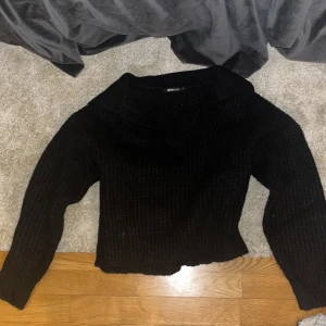Svart stickad tröja från Gina Tricot - Säljer en svart stickad tröja från Gina Tricot. Tröjan har en v-ringad krage och långa ärmar, perfekt för kyligare dagar. Den är både stilren och bekväm.