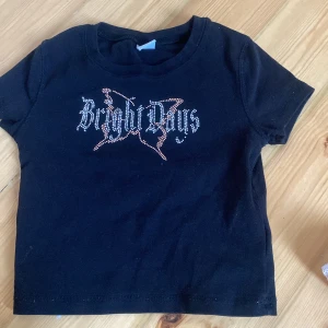 Svart t-shirt med tryck - Cool svart t-shirt med ett unikt tryck i form av text på framsidan. Perfekt för en avslappnad stil. Kortärmad och i mjukt material för bekväm passform.