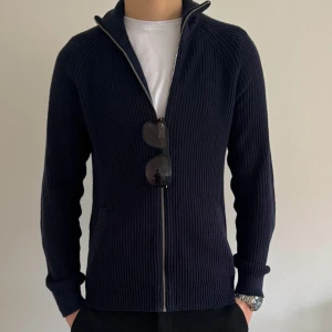 Stickad cardigan kofta - Snygg marinblå stickad cardigan kofta. Storlek S men passar även M. Har en väldigt snygg slimmad passform och är väldigt skön samt stilig. Inte riktigt säker på märket men det står PROJECT. Köptes för 500kr. Mitt pis är 350kr. Inga defekter utan nyskick.