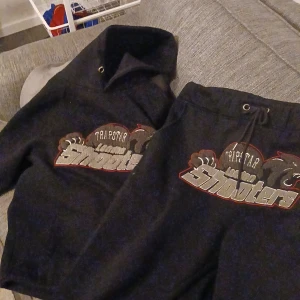 Svart trackuit från trapstar - Säljer en svart hoodie från Trapstar med tryck på framsidan. Hoodien har en klassisk passform med dragsko i huvan och ribbade muddar vid ärmslut och nederkant. Perfekt för en avslappnad stil. Storlek S men sitter som M