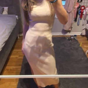 Beige ribbad klänning från Giorgia - Säljer en stilren beige ribbad klänning från Giorgia. Klänningen är ärmlös och har en figurnära passform som framhäver silhuetten. Perfekt för en elegant look.